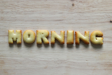 An inscription from the cookies on the wooden background. Text – morning.