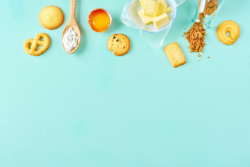 Wooden spoon with flour, chopped butter, raw egg, raisins, cane sugar and mix of shortbread cookies. Simple baking background. Shortbread making. Copy space.