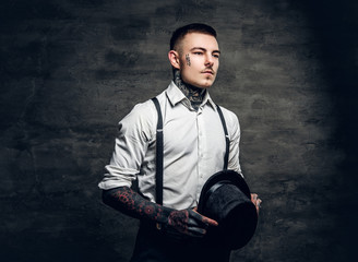 A man with tattoos on his arms and face, dressed in a white shirt and top hat.