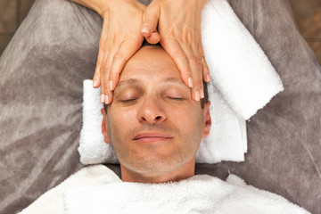 Male face with cream mask, hands of professional beautician