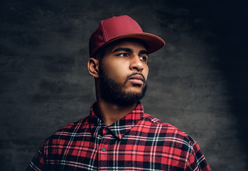 Black bearded male dressed in a red fleece shirt and a cap.