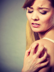 woman scratching her itchy arm with allergy rash