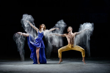 The dancing couple in the darkness, make white dust cloud in the dance movement.