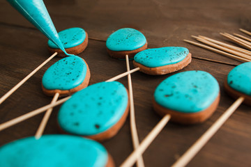 Preparing easter cookies with blue icing for decoration on rustic wooden table closeup