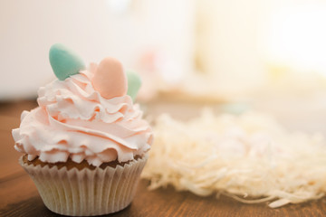 Delicious cup cake with white cream on wooden table closeup. Background with copyspace for text. Easter gift, small business, delivery of sweets, culinary craftmanship concept