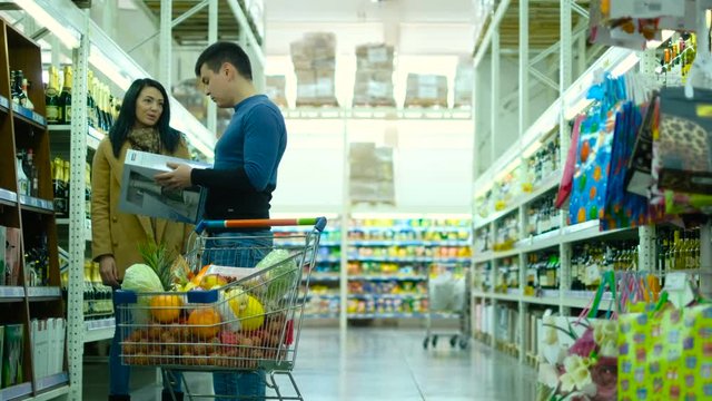 Image of happy couple choosing goods in supermarket