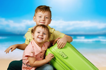 Fototapeta premium Brother with sister in the background of the sea with a suitcase . the concept of summer vacation