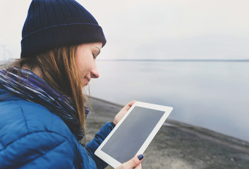 Smiling young woman holding tablet standing on the city waterfront