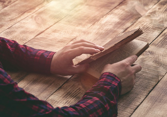 Male hands holding an old book on a wooden table