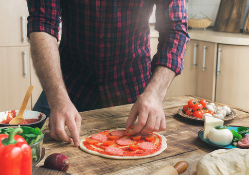 Man cooking pizza in home kitchen on wooden table