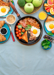 Fried egg, beans, tomatoes, bacon, toast various fruits, juice, coffee