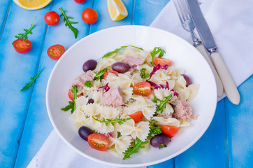 Pasta salad with tuna, olives, cherry tomatoes and arugula