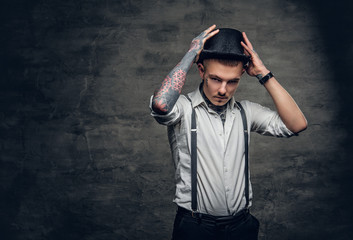 A man with tattoos on his arms and face, dressed in a white shirt and top hat.
