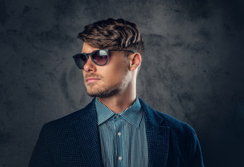 Fototapeta premium Portrait of stylish male in sunglasses over grey background.