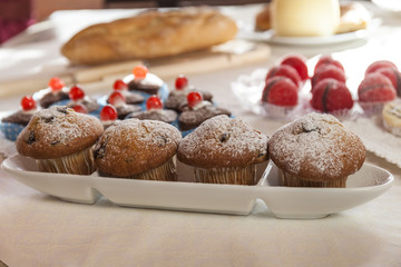 Morning breakfast with muffins and other sweet bakery. Bread in the background