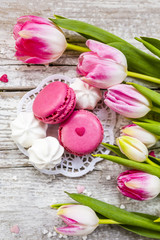 Spring tulips and French macaroons, delicious cookies on wooden backround.