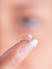 Young woman with contact lens on her finger.