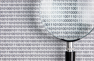 magnifying glass on a binary code