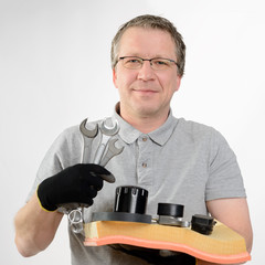 Auto Mechaniker mit Ersatzteilen in der Hand, lächelt in die Kamera, Werkstatt, Service, Reparatur