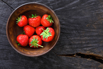 Red fresh strawberries on black rustic wood background