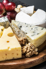 Cheese plate with fruits and nuts on a wooden table