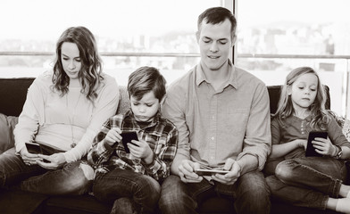 Cheerful family members spending time playing with smartphones