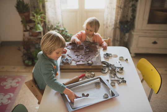 Sisters preparing gingerbread cookies at home