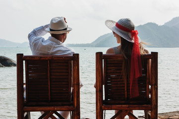 a young man and a girl sitting on the beach