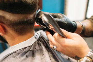 Man making curly haircut at barber shop closeup. Stylist hand with trimmer cutting male head. Hairstyle, beauty, modern lifestyle, fashion concept