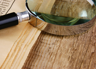 edge of the old newspaper and magnifying glass on a wooden background