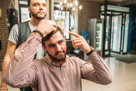 Confident man tell about haircut he want. Businessman show stylist how to cut his hair, free space. Barber shop, beauty, fashion, modern lifestyle concept