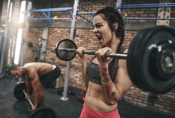 Fit couple lifting barbells in the gym.