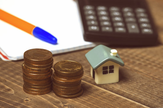 Coins, house, calculator and notepad
