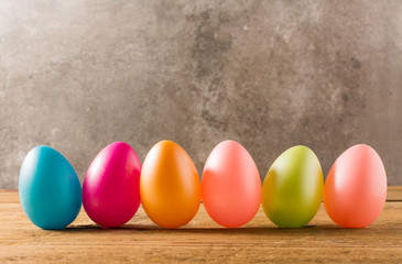 Easter eggs on wooden table and stone background