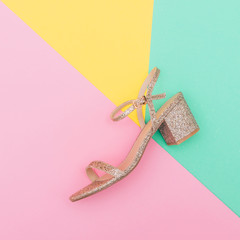 creative concept one sandals with gold color and glitter on pastel background. minimal flat lay