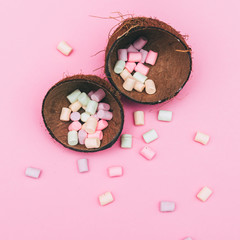 marshmallow is scattered from a coconut on a pink background. minimal concept