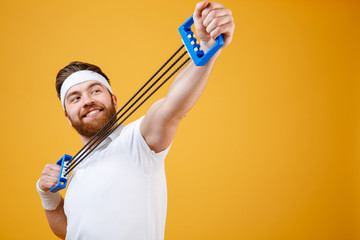 Portrait of a cheerful sportsman doing fitness exercises with expander