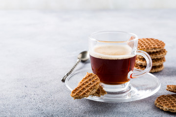 Glass cups of coffee with mini stroopwafel, syrupwaffles cookies on light gray background with copy space.