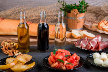 Ingredients on plates for preparation bruschetta near bottle with sauce. Italian cuisine food antipasto, crostini.