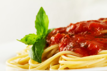 Tasty colorful appetizing cooked spaghetti italian pasta with tomato sauce bolognese and fresh basil. Closeup.