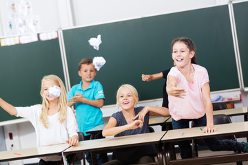 Kinder in Grundschule werfen mit Papier