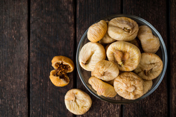 Dried figs in glass bowl on wooden background.