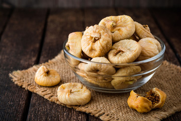 Dried figs in glass bowl on wooden background.