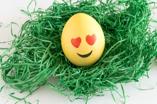 Happy easter: emoji as easter egg in green gras - heart shaped eye
