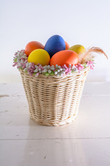 basket with easter eggs and feathers