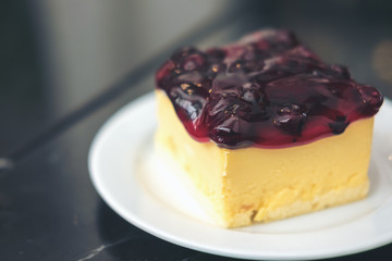 A blueberry cheese cake in white ceramic plate on marble table