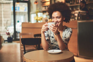 Mixed race woman in coffee shop having coffee and smiling