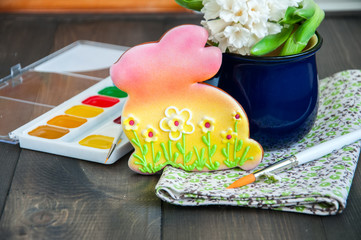 Decorated Easter Bunny Cookies Hyacinth in a jar Paints and Brushes on a wooden background. Easter concept.