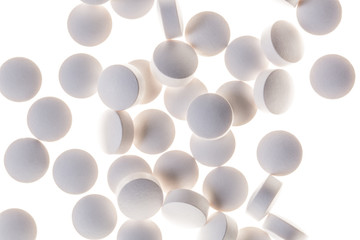 Round white pills sit on a table.