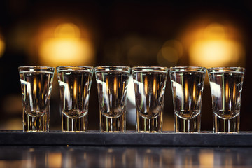 Alcoholic shots of tequila or strong drink in small glasses,Barman at work,Barman pouring hard spirit into glasses in detail, with lime garnish ready to be served,concept about service and beverages